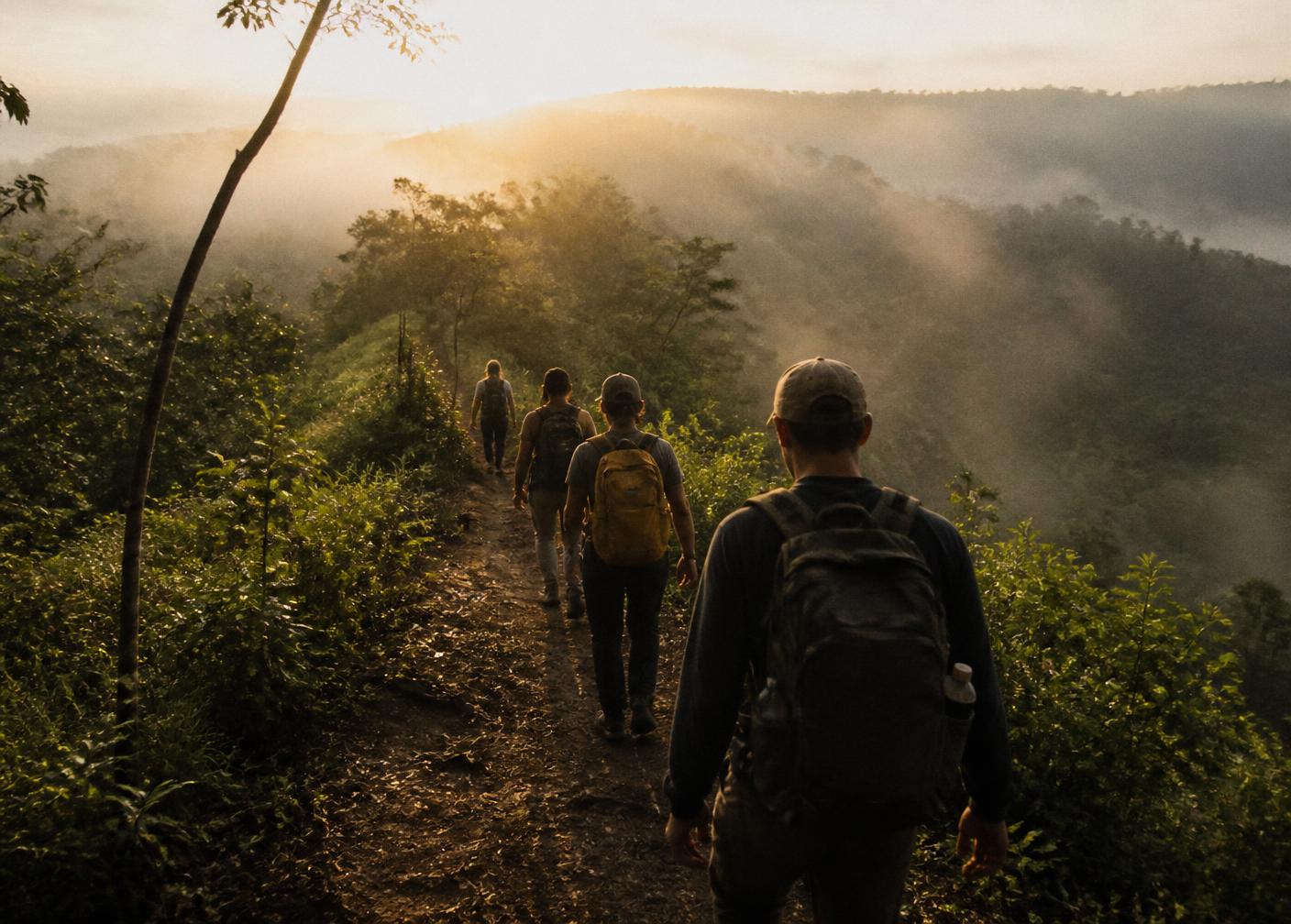 Small group hiking a misty ridgeline trail at sunrise